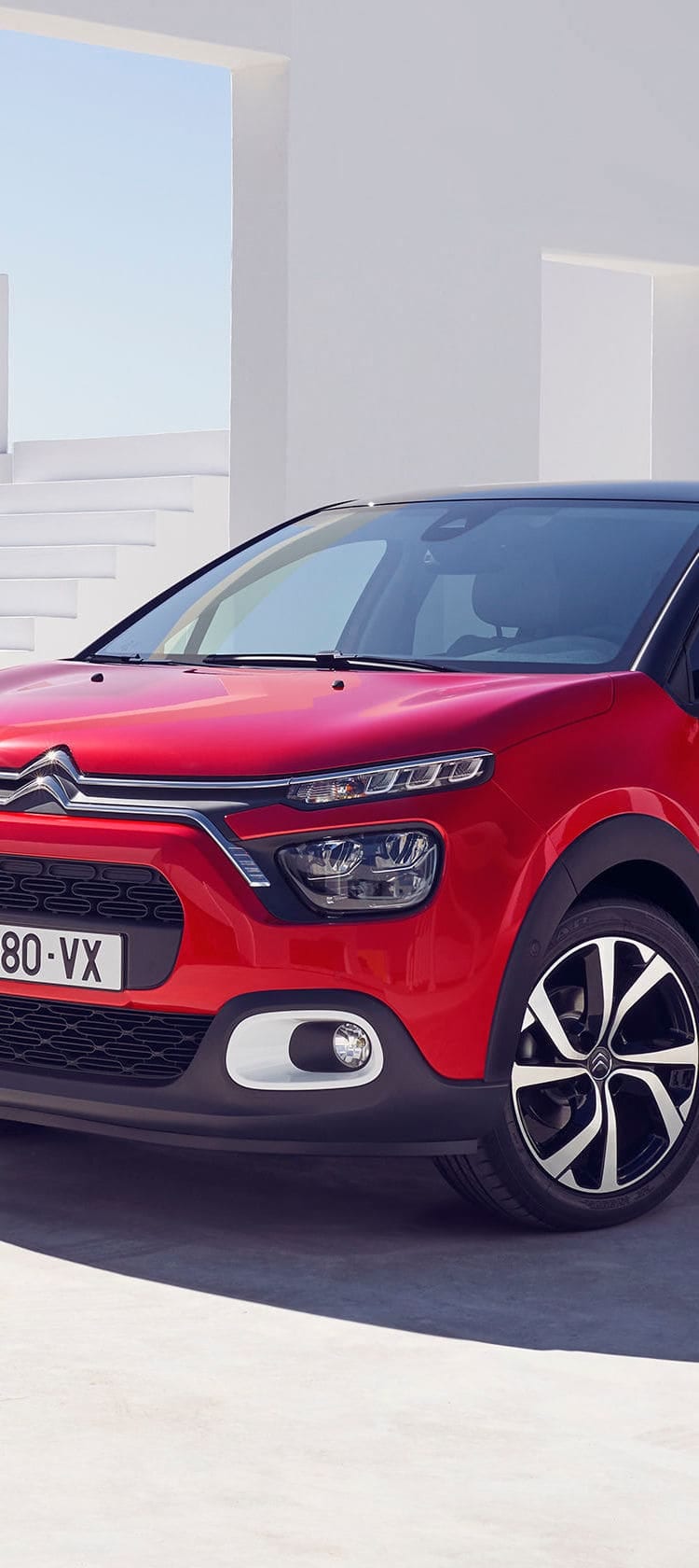 Citroën C3 Rouge avec coucher de soleil et ville en fond